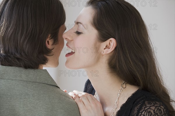 Woman whispering in boyfriend’s ear.