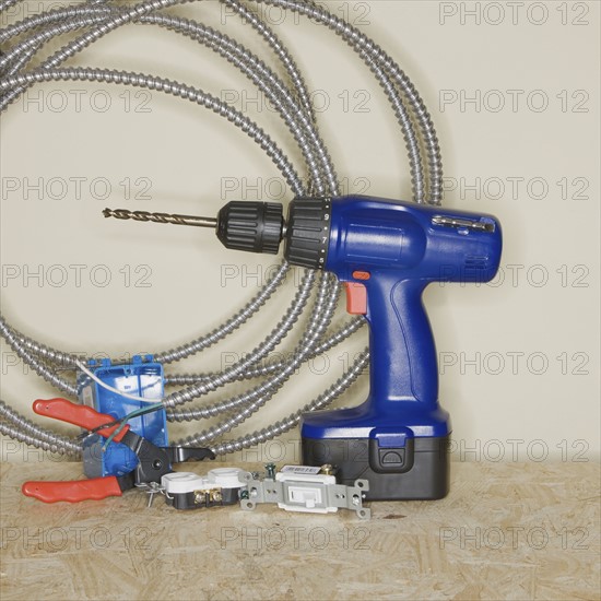 Cordless drill next to wire cutters and cable.