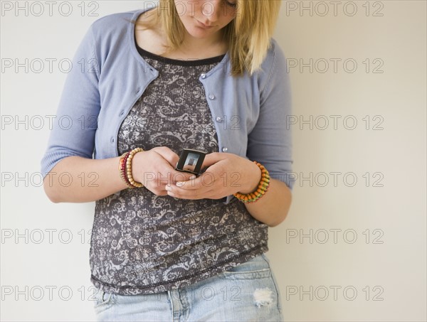 Teenaged girl dialing cell phone.