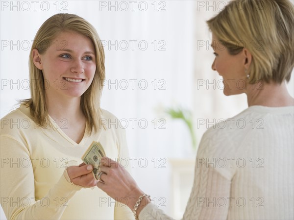 Mother giving money to teenaged daughter.