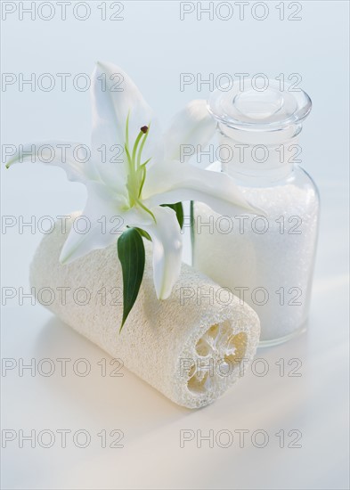 Flower and loofah next to bath salts.