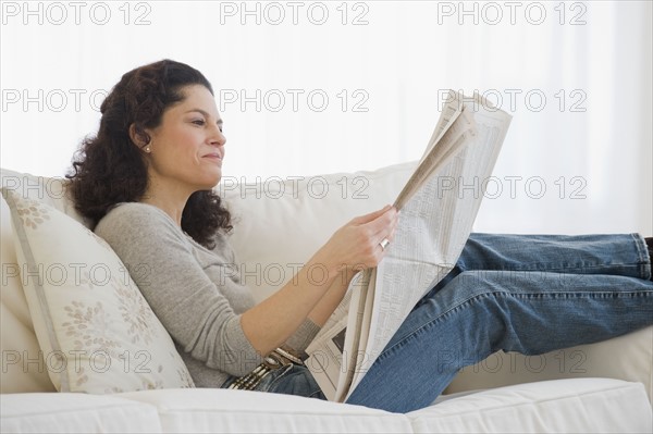 Hispanic woman reading newspaper.
