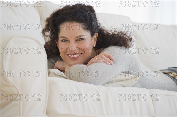 Hispanic woman laying on sofa.