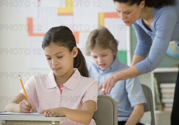 Hispanic girl writing at school desk.