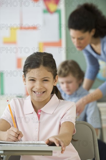 Hispanic girl writing at school desk.