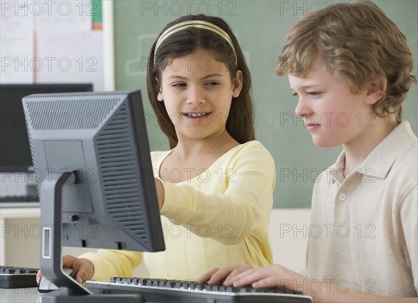 Multi-ethnic school children looking at computers.