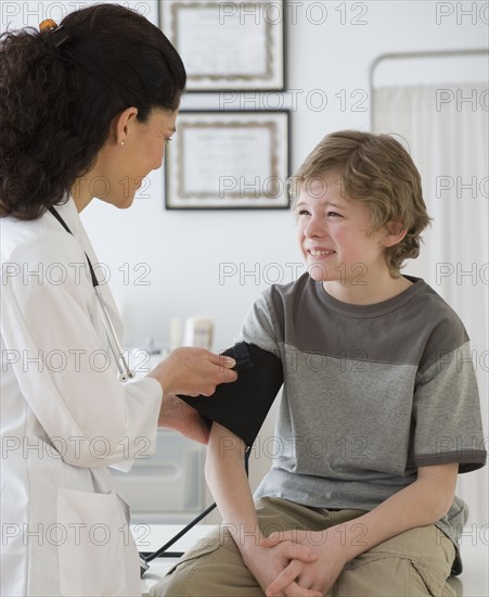 Hispanic female doctor taking child’s blood pressure.