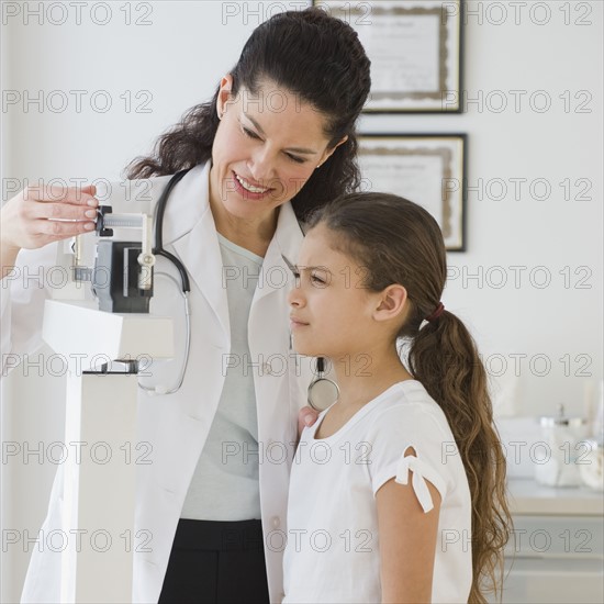 Hispanic female doctor weighing child.