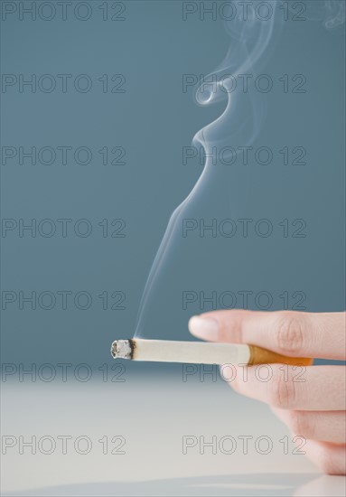 Woman holding lit cigarette.