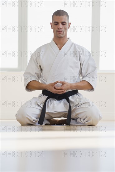 Hispanic male karate black belt meditating.