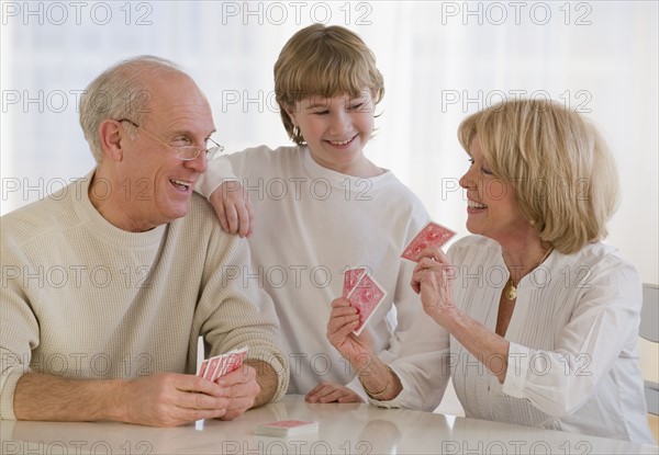 Grandson watching grandparents play cards.