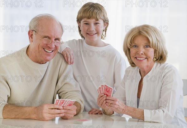 Grandson watching grandparents play cards.