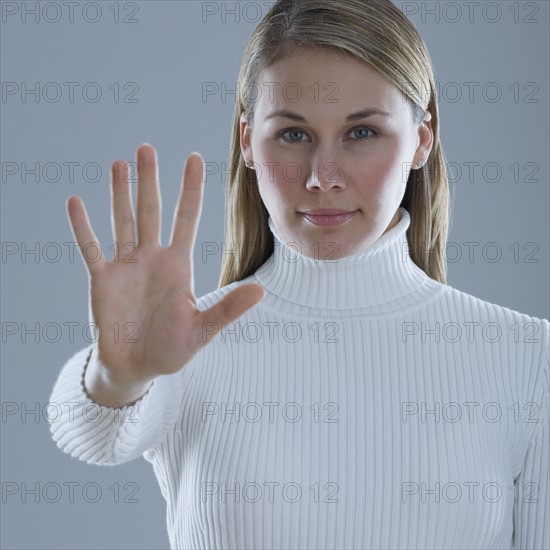 Woman holding up hand with palm out.