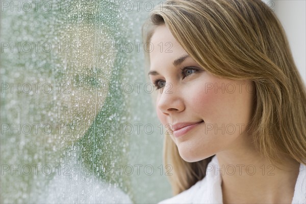 Woman looking out rainy window.
