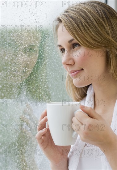 Woman looking out rainy window.