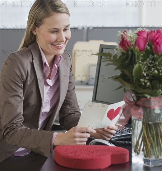 Businesswoman reading Valentine’s Day card.