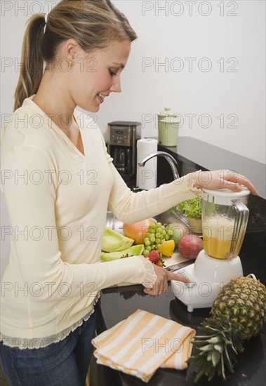 Woman pushing button on blender.