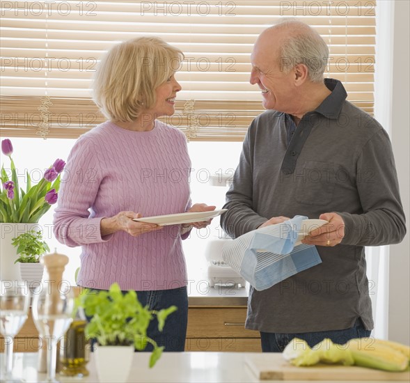 Senior couple drying dishes.