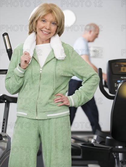 Senior woman next to exercise machines.