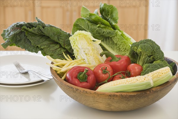 Bowl of vegetables next to dishes.