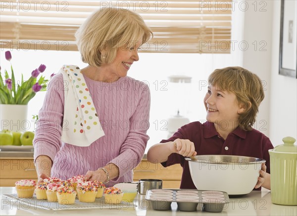 Grandmother and grandson baking cupcakes.