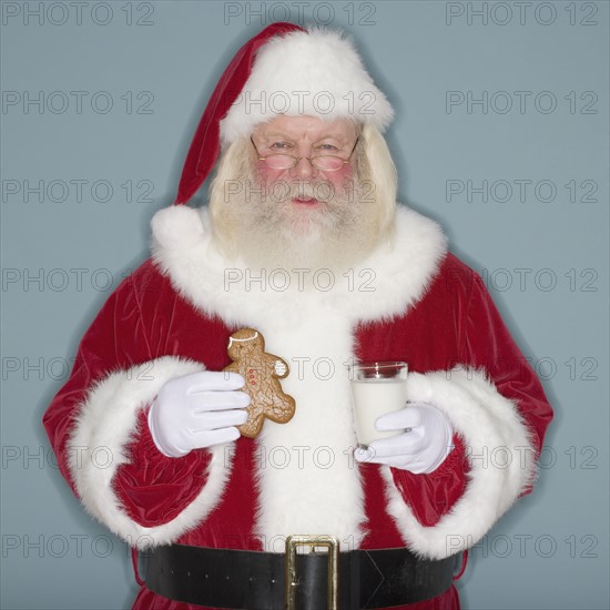 Santa Claus holding cookie and milk.