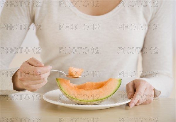 Woman eating melon wedge.