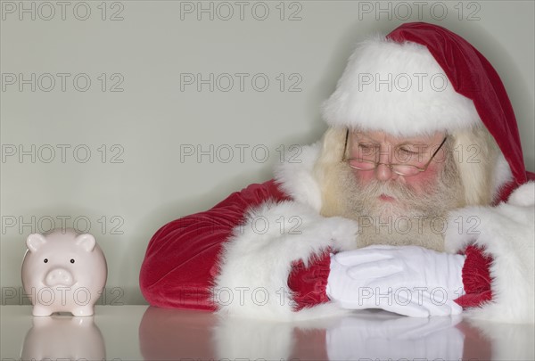 Santa Claus looking at piggy bank.