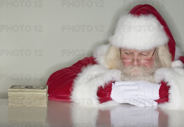 Santa Claus looking at stack of money.