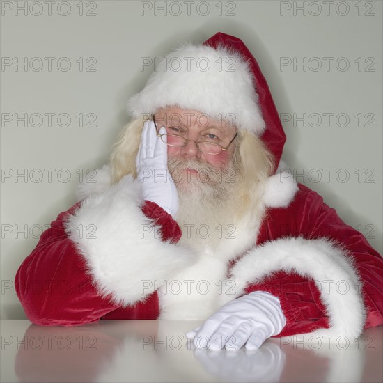 Santa Claus leaning on table.