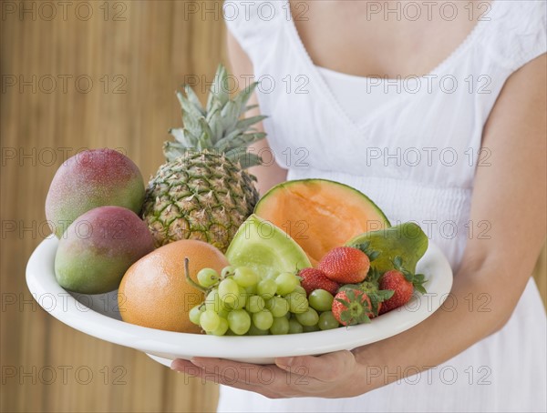 Woman holding plate of fruit.