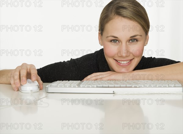 Woman leaning on table next to keyboard.