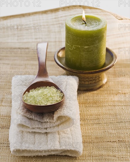 Bath salt in spoon next to candle.