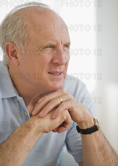 Senior man resting chin on hands.