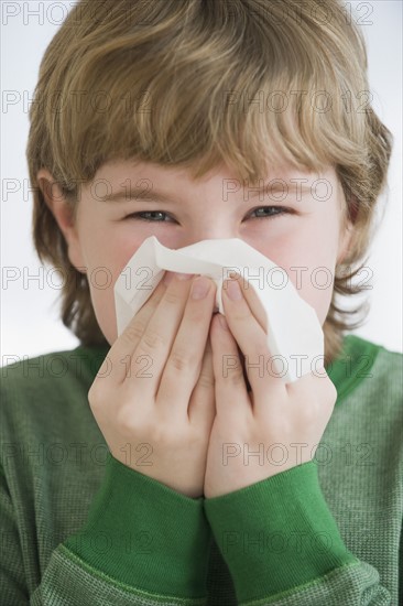 Boy blowing nose.