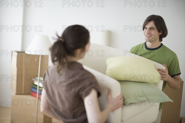 Couple carrying bedding in new house.