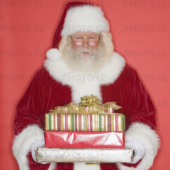 Santa Claus holding stack of gifts.