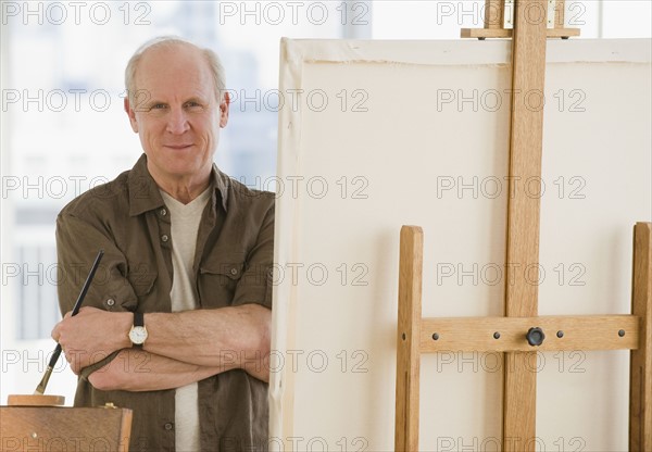 Senior man standing next to easel.