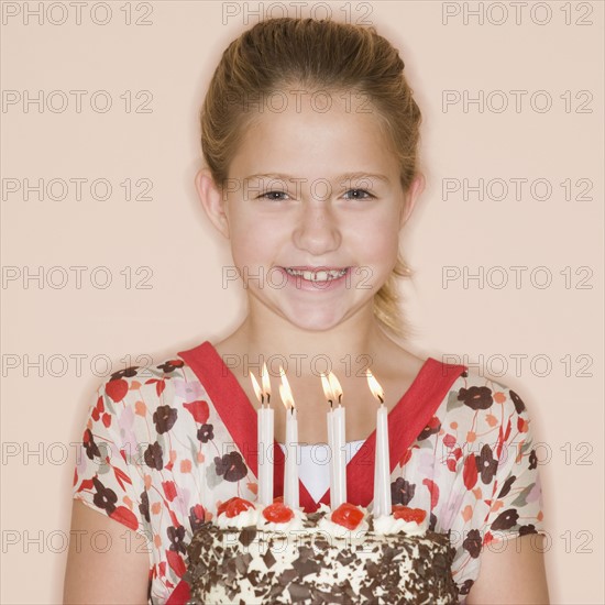 Girl holding birthday cake with lit candles.