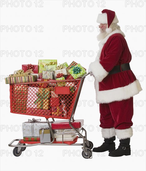 Santa Claus pushing shopping cart full of gifts.