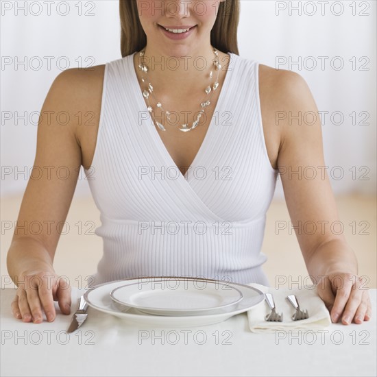 Woman sitting at empty place setting.