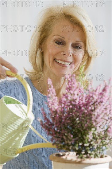 Senior woman watering plant.