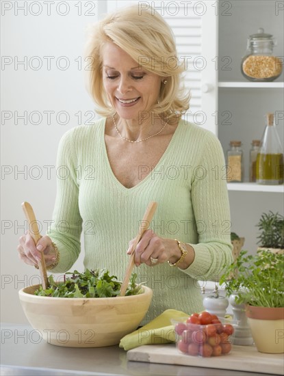 Senior woman tossing salad.