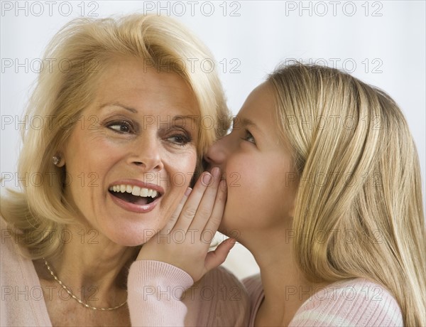 Grandmother and granddaughter telling secret.