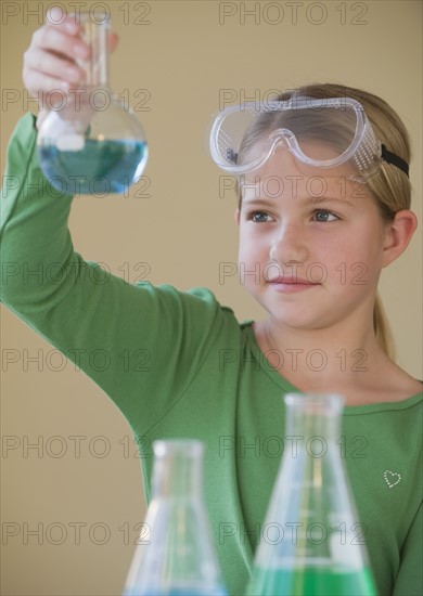 Girl in science class looking at beaker.