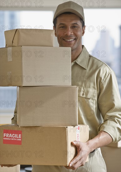 African delivery man carrying stack of packages.