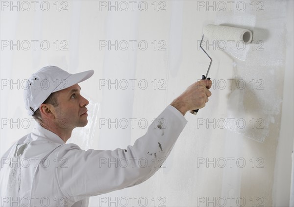 Male painter painting with paint roller.