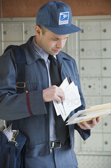 Male postal worker looking at mail.