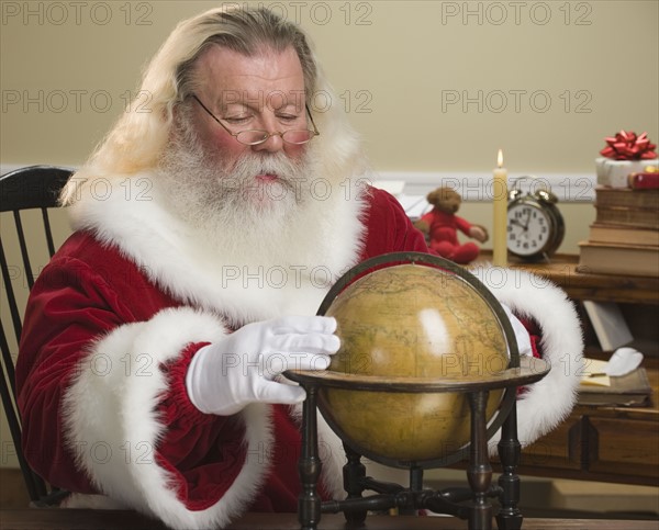 Santa Claus looking at globe.