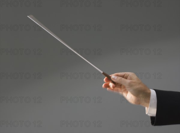 Male conductor’s hand holding baton.